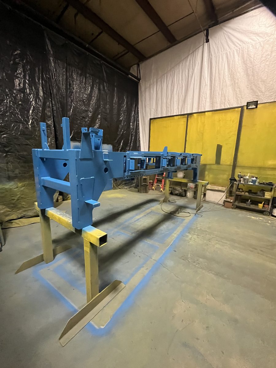 Painted blue log-handling frame assembled on stands inside the Roebuck plant