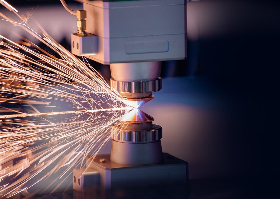 Laser cutting head throwing sparks as it cuts steel plate